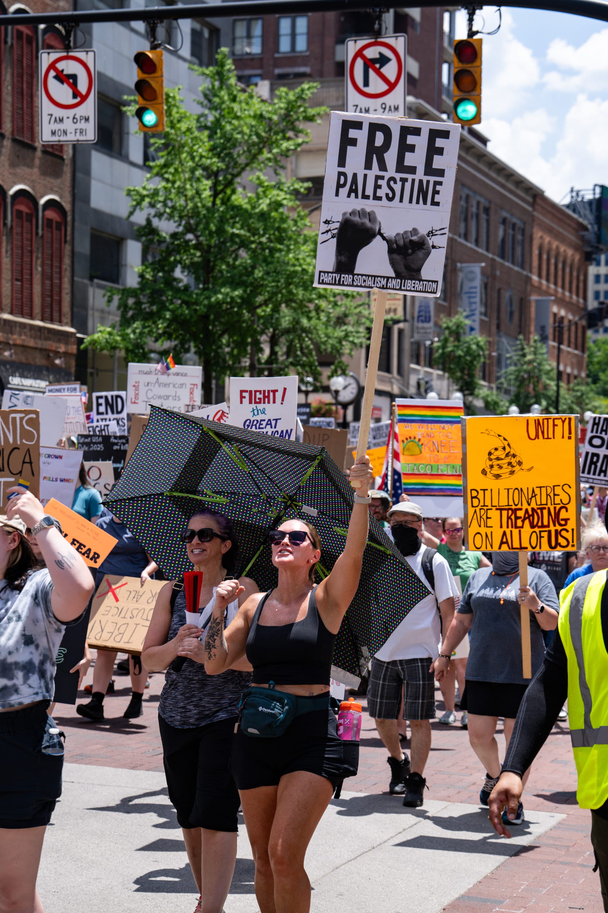 A woman marches with a sign raised overhead, a 'Free Palestine' placard above the crowd.