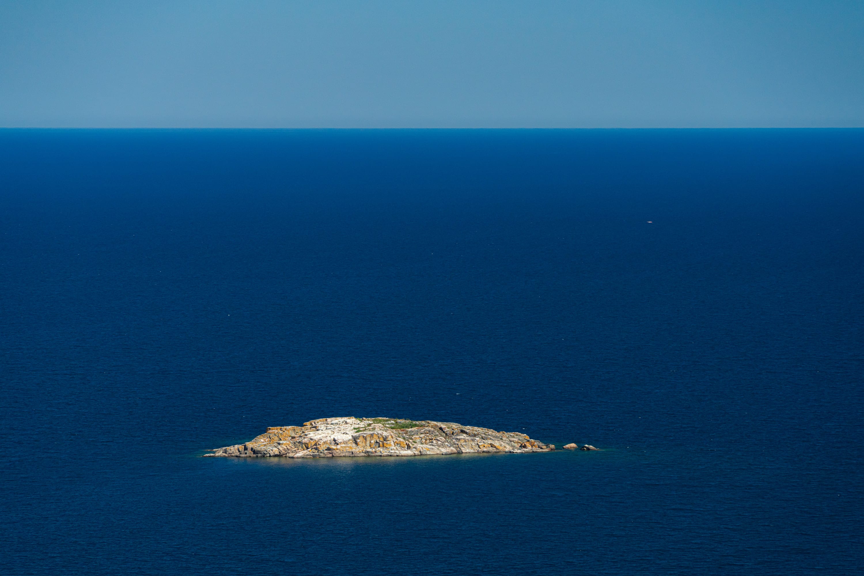 A small rocky island alone in deep blue water.